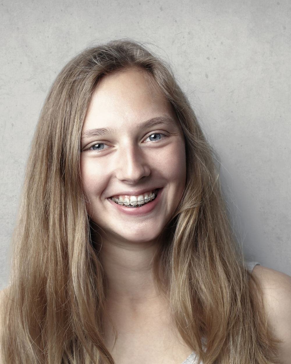 Patient smiling with metal orthodontic braces after treatment at The Port Dental Clinic in Calgary NE