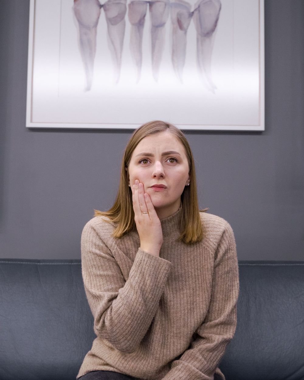 Patient holding her jaw in discomfort at The Port Dental Clinic in Calgary NE