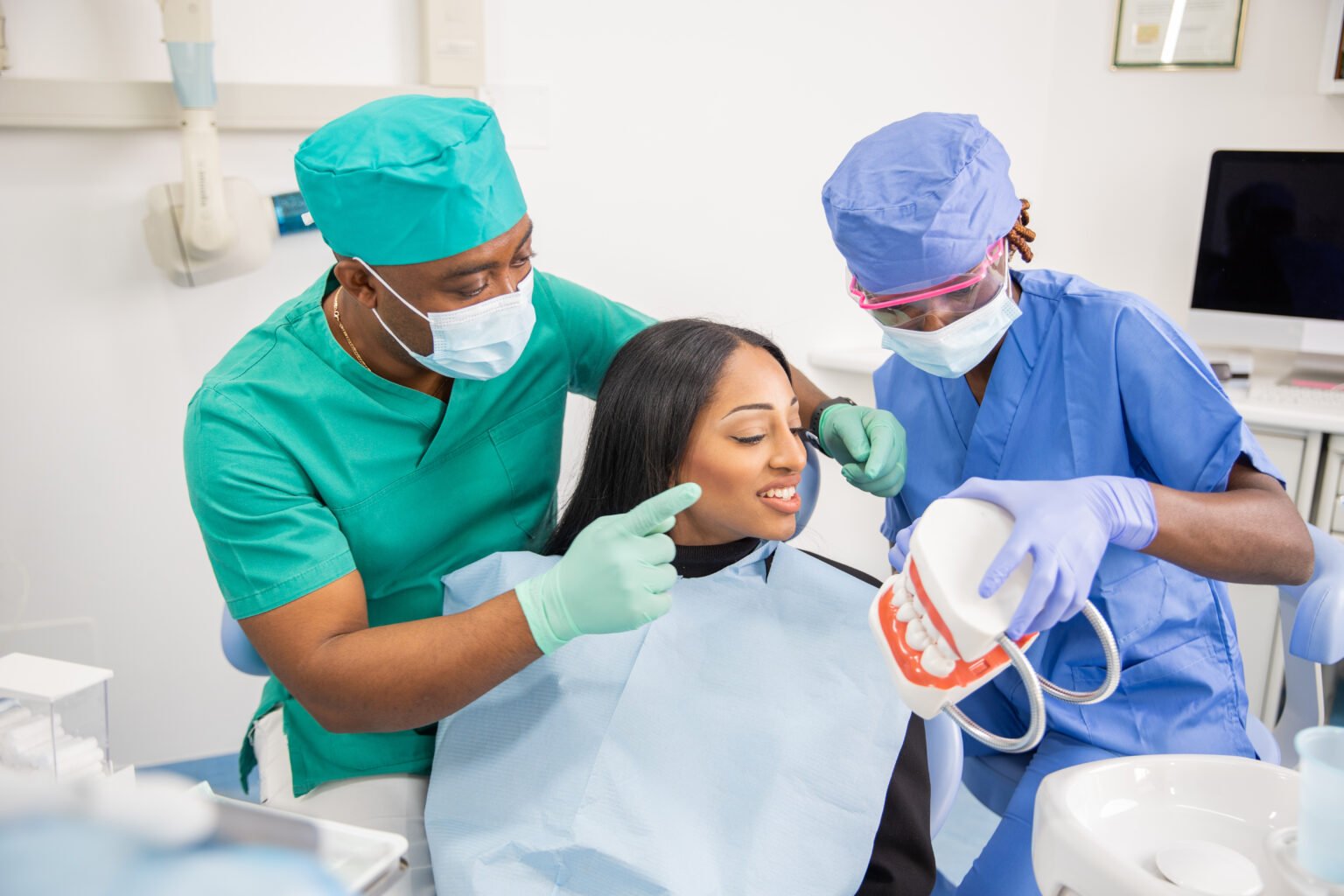 A dentist gives a consultation to a patient and with his assistant they explain the teeth.