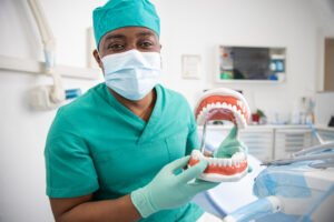 An african dentist holding a dentition teeth model in his hand, dental health concept.